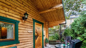 A wooden cabin with a porch, a bench, a table with chairs, and a door with a window. - Holiday Home 'Häuschen Grau' with Private Garden and Wi-Fi (Scheibenberg)