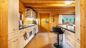 A wooden interior with a kitchen area, a dining space, and a door leading to another room. - Holiday Home 'Haus Grün' suitable for wheelchairs (Scheibenberg)