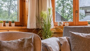 A cozy room with a wooden window, a grey sofa, and small potted plants on the windowsill. - Holiday Home 'Haus Grün' suitable for wheelchairs (Scheibenberg)