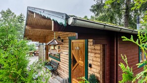 A wooden cabin with a green door, a small porch, and a bench. - Holiday Home 'Haus Grün' suitable for wheelchairs (Scheibenberg)