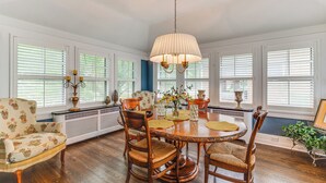 Un comedor con una mesa de madera, sillas y una araña.