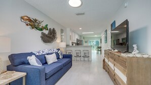 Ein modernes Wohnzimmer mit einem blauen Sofa, einem Holzschrank und einem Flachbildfernseher.