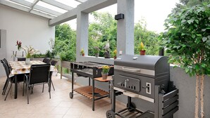 Un patio exterior con una estación de parrilla, una mesa de comedor y sillas.