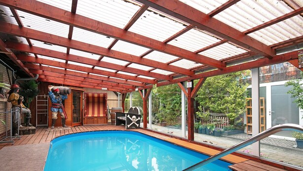 Una piscina interior con muelle de madera, zona cubierta con techo metálico y decoración temática de piratas.