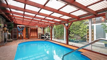 Une piscine intérieure dotée d’une terrasse en bois, d’un espace couvert avec un toit en métal et d’une décoration sur le thème des pirates.