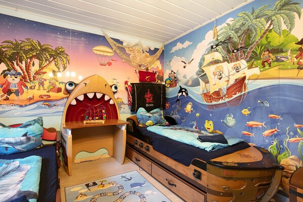 A child's bedroom with a pirate-themed mural, a bunk bed, and a desk.