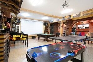 A billiards room with a pool table, a foosball table, and a table tennis table.