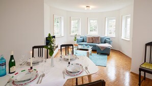 Een eetgedeelte met een tafel voor vier personen, een bank op de achtergrond en een plant op tafel.