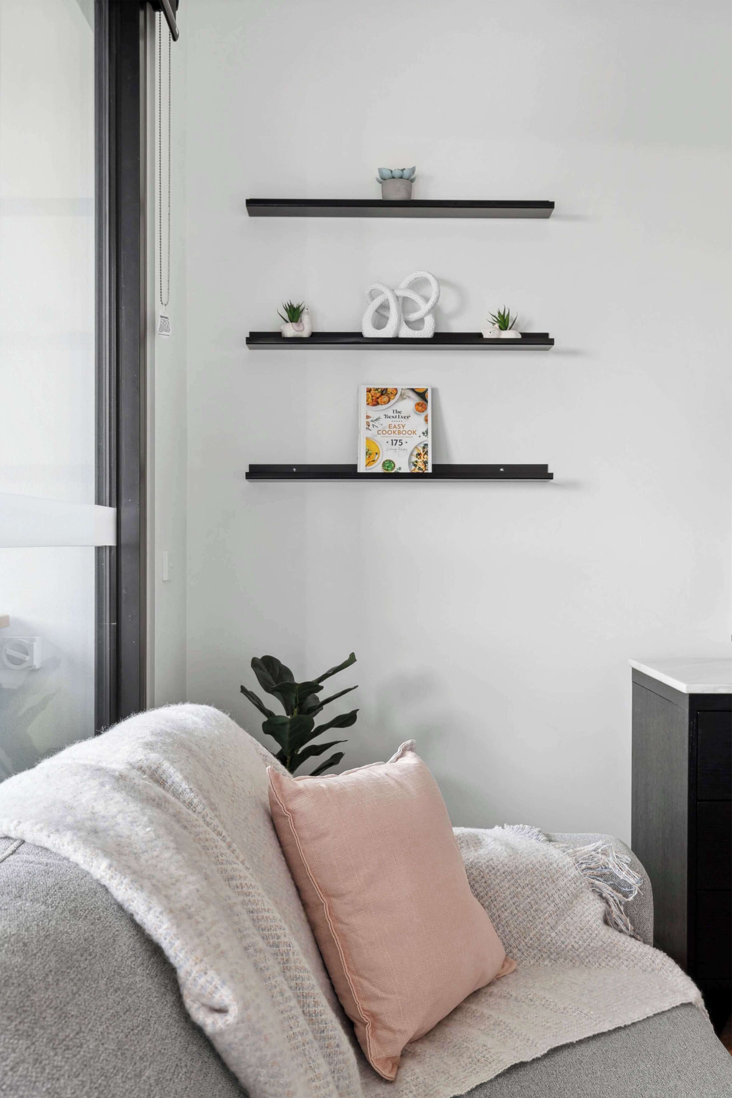 A modern room with a bed, a window, and three black shelves with decorative items.