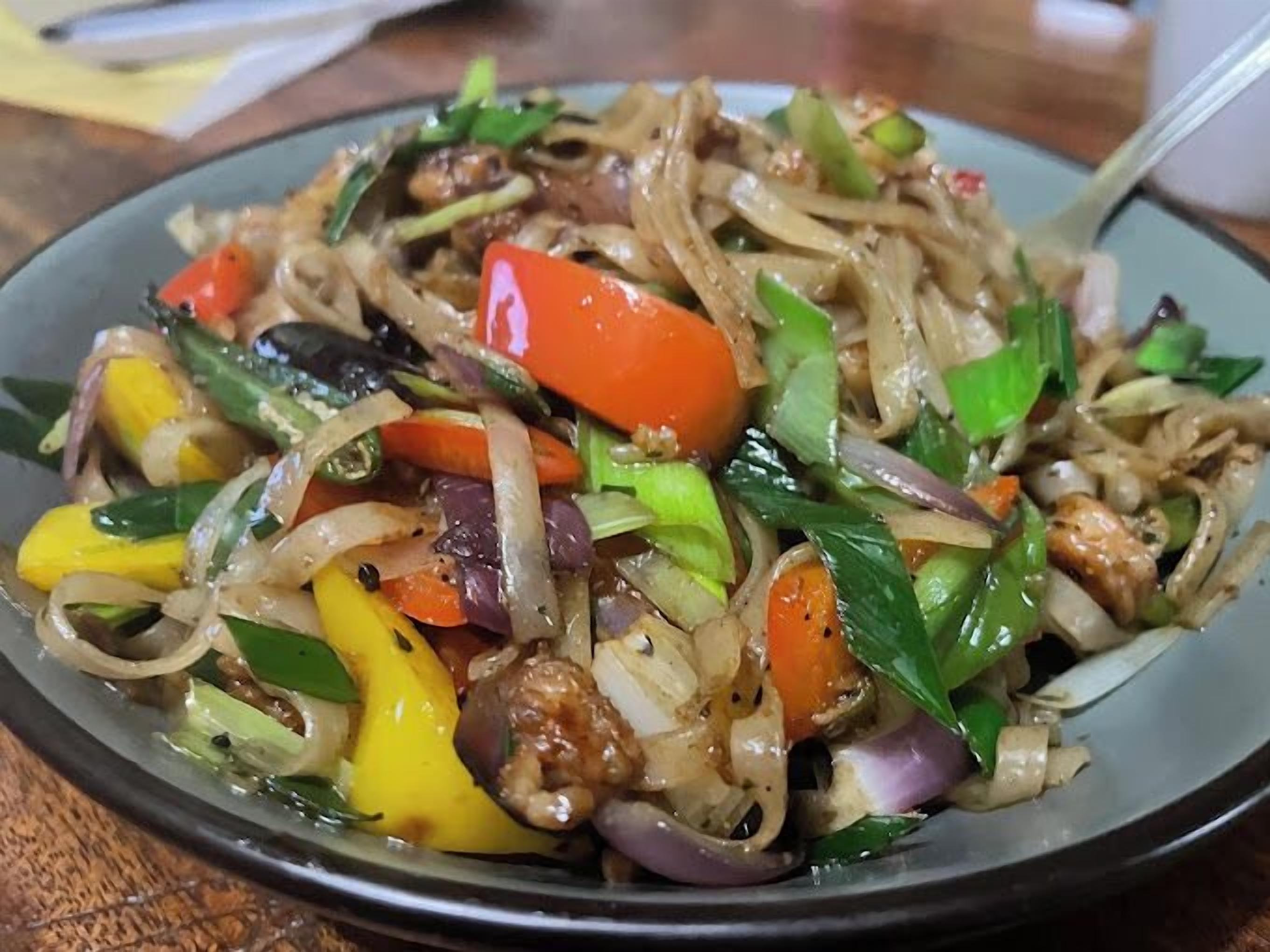 A plate of stir-fried noodles with vegetables and meat.
