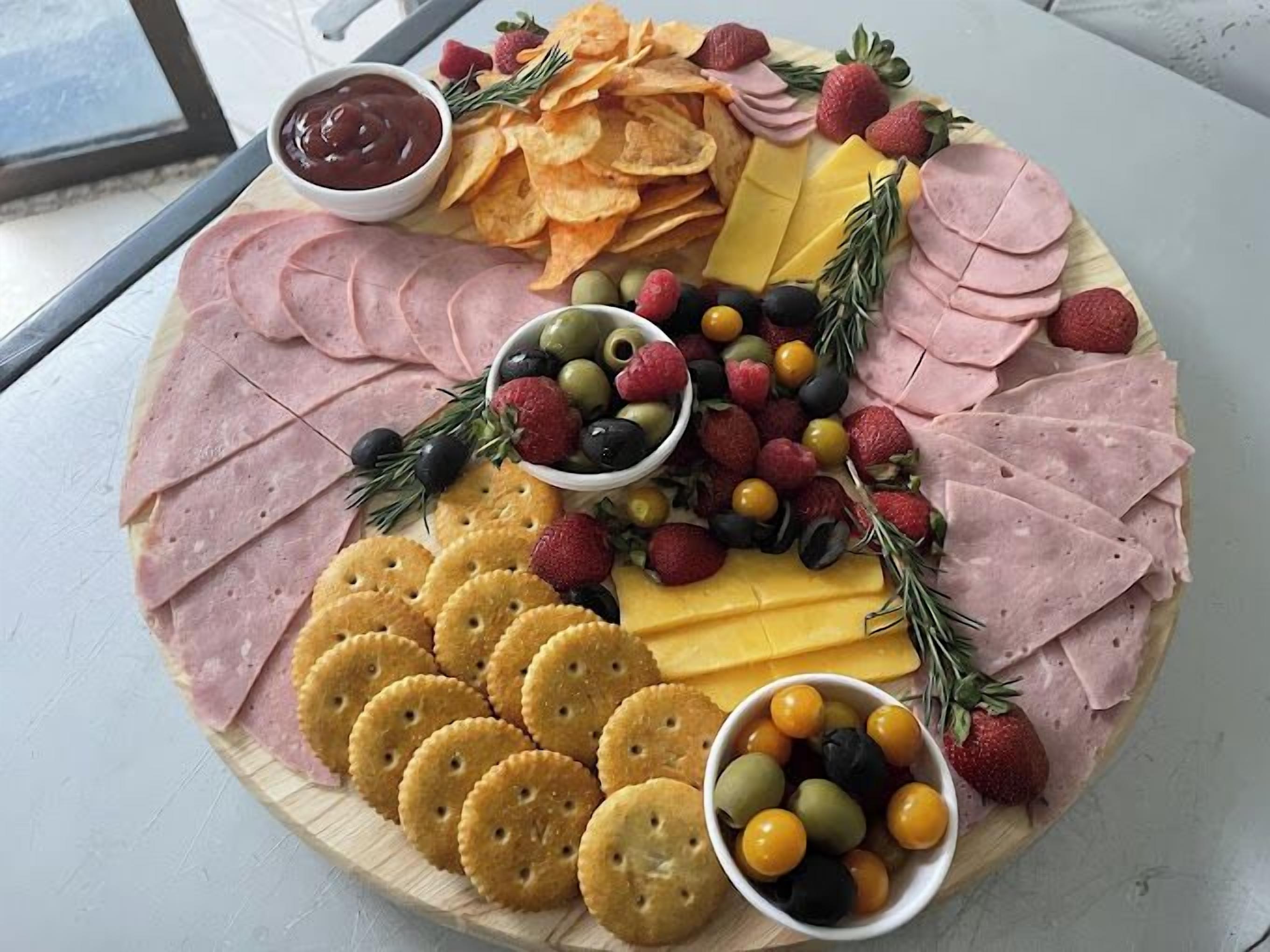 A charcuterie board with various meats, cheeses, crackers, and fruits.