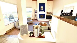 A living room with a fireplace, a sofa, a coffee table, and a view of the outdoors.