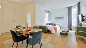 A modern living room with a dining area, a sofa, and a bed. - Splendid Apartment in the Heart of the Chic 16th (Paris)
