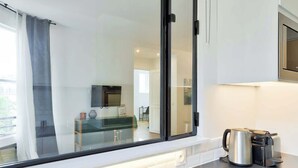 A modern kitchen with a large window, a coffee maker, and a television. - Splendid Apartment in the Heart of the Chic 16th (Paris)