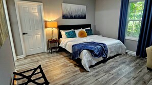 A bedroom with a bed, a nightstand, a lamp, a chair, and a window with curtains.