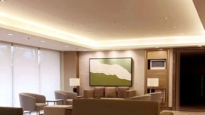 A modern living room with a sectional sofa, a dining area with chairs, and a large abstract painting on the wall. - Acellyne's Suites at Green 2 Residences (Dasmarinas)