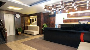 A reception area with a reception desk, a sofa, a clock, and a staircase. - Octave Verdisso Hotel (Bengaluru)
