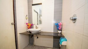 A bathroom with a sink, mirror, toilet, and a trash bin. - Octave Verdisso Hotel (Bengaluru)