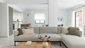 En moderne stue med en modulsofa, et sofabord og et spiseområde i baggrunden.