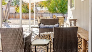 Une terrasse extérieure avec des meubles en osier et un tapis à motifs.