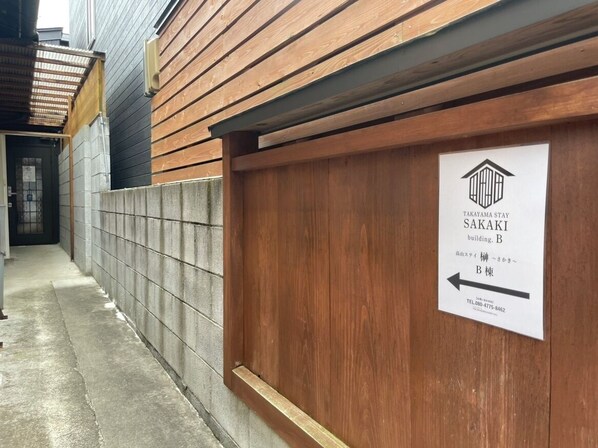 Un couloir avec un mur en bois et une pancarte indiquant le bâtiment B de l’établissement Takayama Stay Sakaki.