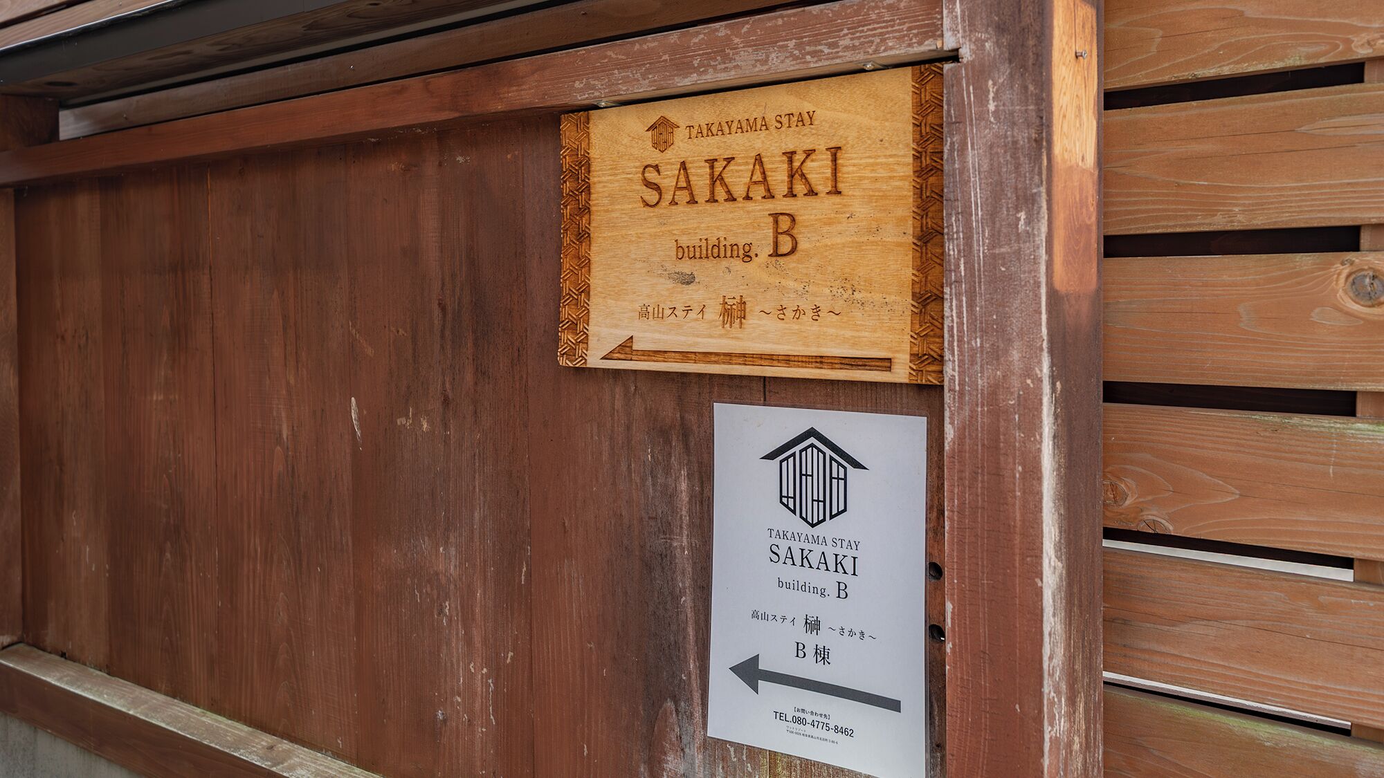 A wooden sign with the name 'SAKAKI building B' and a directional arrow pointing left.