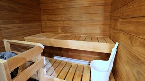 Eine Sauna mit Holzbänken und einem weißen Kunststoffstuhl.