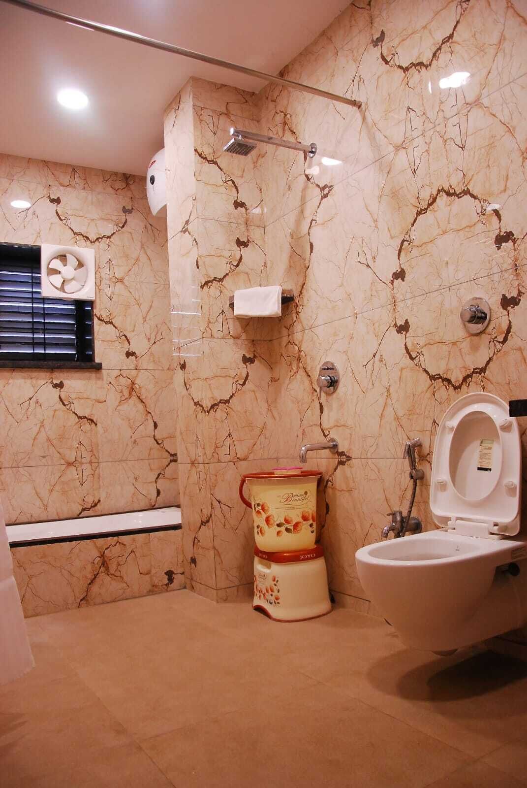 Een badkamer met een marmeren wand, een toilet, een bidet en een douche.