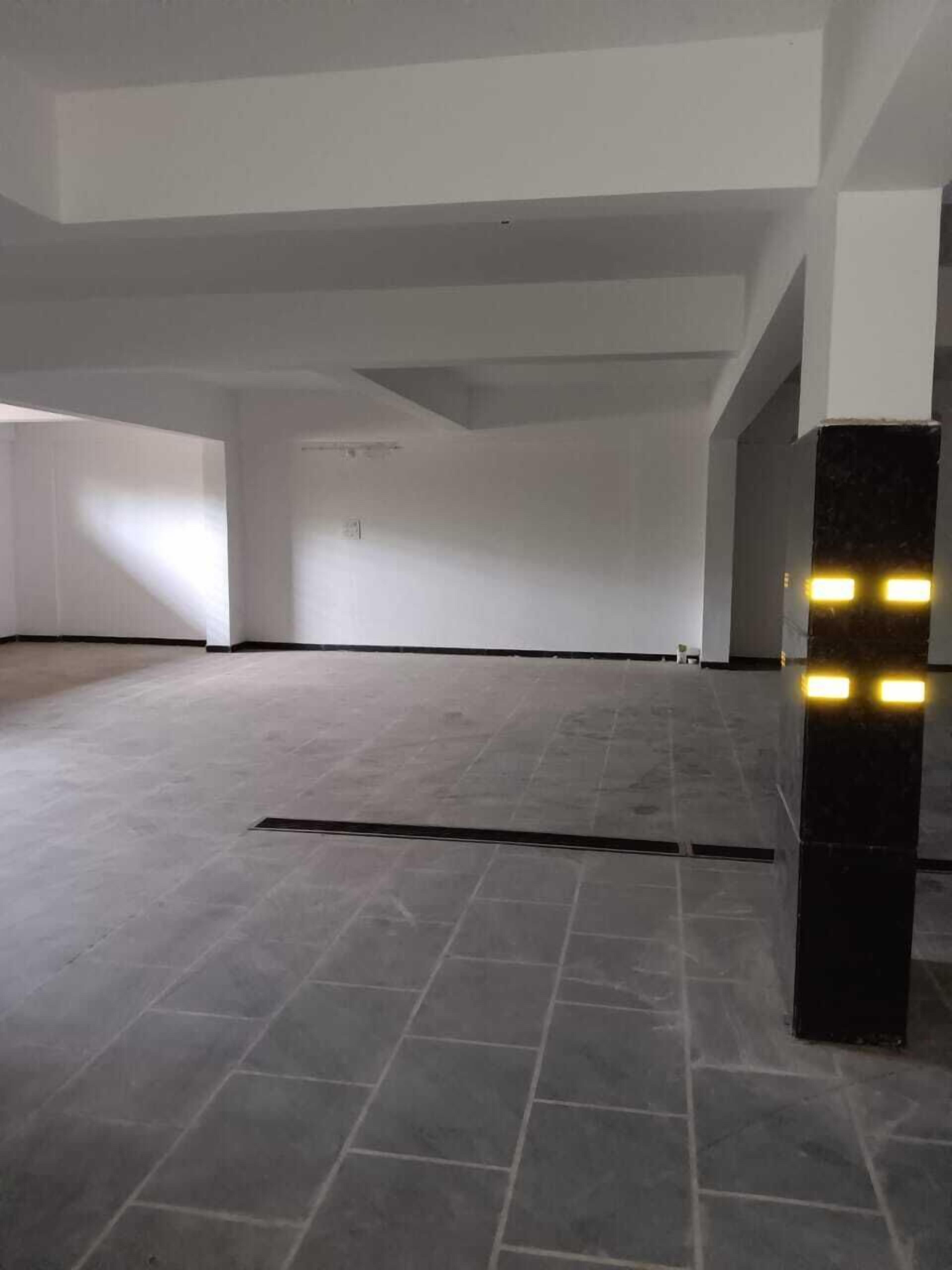 A spacious, empty room with a tiled floor and a black pillar with lights.