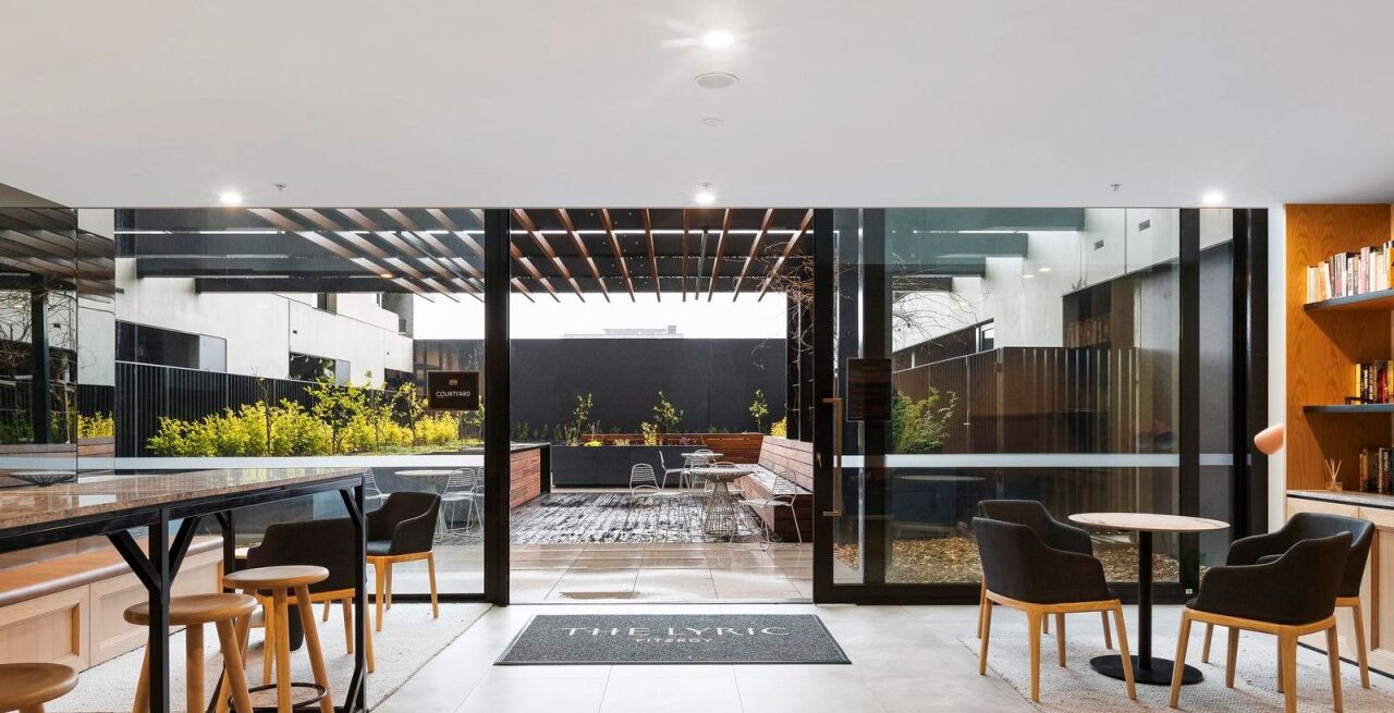 An open-plan office space with a view of the city, modern furniture, and a small outdoor seating area.