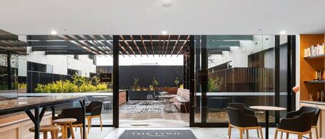 An open-plan office space with a view of the city, modern furniture, and a small outdoor seating area.
