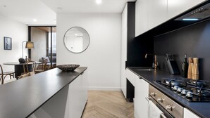 Uma cozinha moderna com uma ilha central, fogão e área de refeições com cadeiras e mesa.