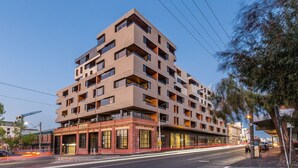 Um edifício com vários andares e design arquitetônico moderno, com uma combinação de varandas e janelas.