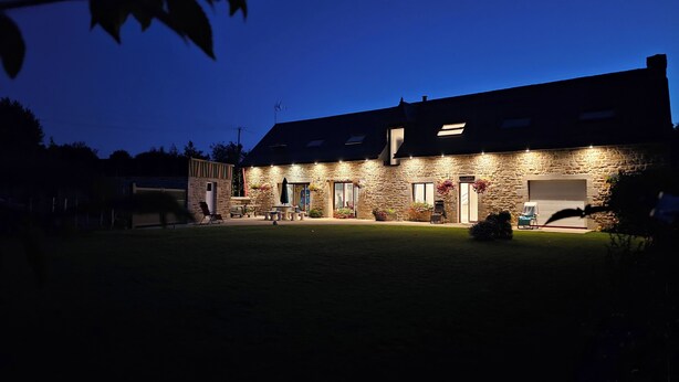 Un bâtiment en pierre avec un toit plat, plusieurs portes et un garage.