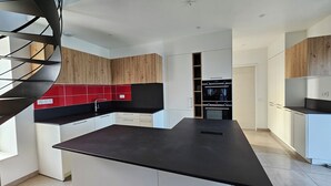 Une cuisine moderne dotée d’un îlot central, de meubles en bois et d’un pare-feu rouge.