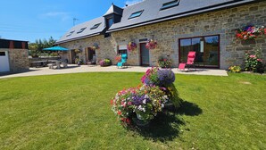 Un bâtiment en pierre doté d’un toit en pente, d’une terrasse et de compositions florales.