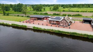 A riverside building with brick architecture, solar panels, and a covered outdoor area.