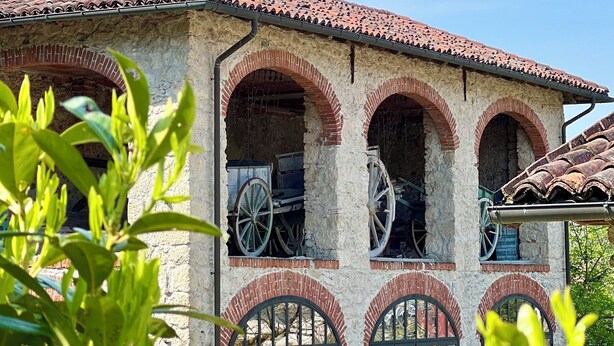 A building with a tiled roof and arched windows, featuring old-fashioned machinery inside. - Casale Milleseicento (Gavi)