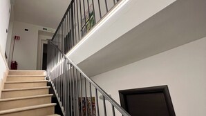 A staircase with beige carpeted steps, metal railings, and a light fixture running along the handrail. - Casale Milleseicento (Gavi)
