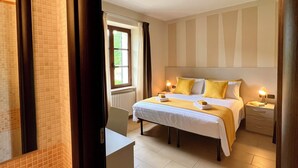 A hotel room with a bed, bedside tables, a window, and a bathroom with a sink and mirror. - Casale Milleseicento (Gavi)