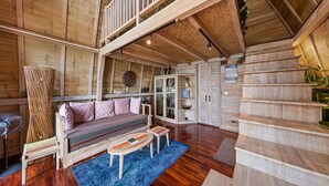 A spacious wooden cabin with a loft bedroom, a cozy sitting area with a sofa and coffee table, and a staircase leading to the upper level.