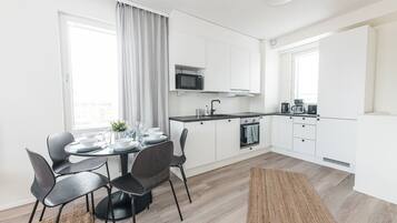 Una cocina moderna con armarios blancos, microondas y cafetera.