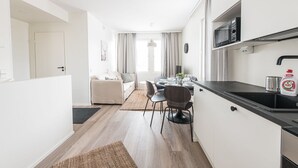 A modern kitchen with a black countertop, a microwave, and a sink. There is a dining area with a table and chairs. - Forenom Serviced Apts Vantaa Koivuhaka (Vantaa)