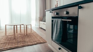 A modern kitchen with a built-in oven, a dining area with a table and chairs, and a living room with a sofa. - Forenom Serviced Apts Vantaa Koivuhaka (Vantaa)