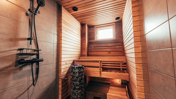 A sauna with wooden benches, a showerhead, and a trash bin. - Forenom Serviced Apts Vantaa Koivuhaka (Vantaa)