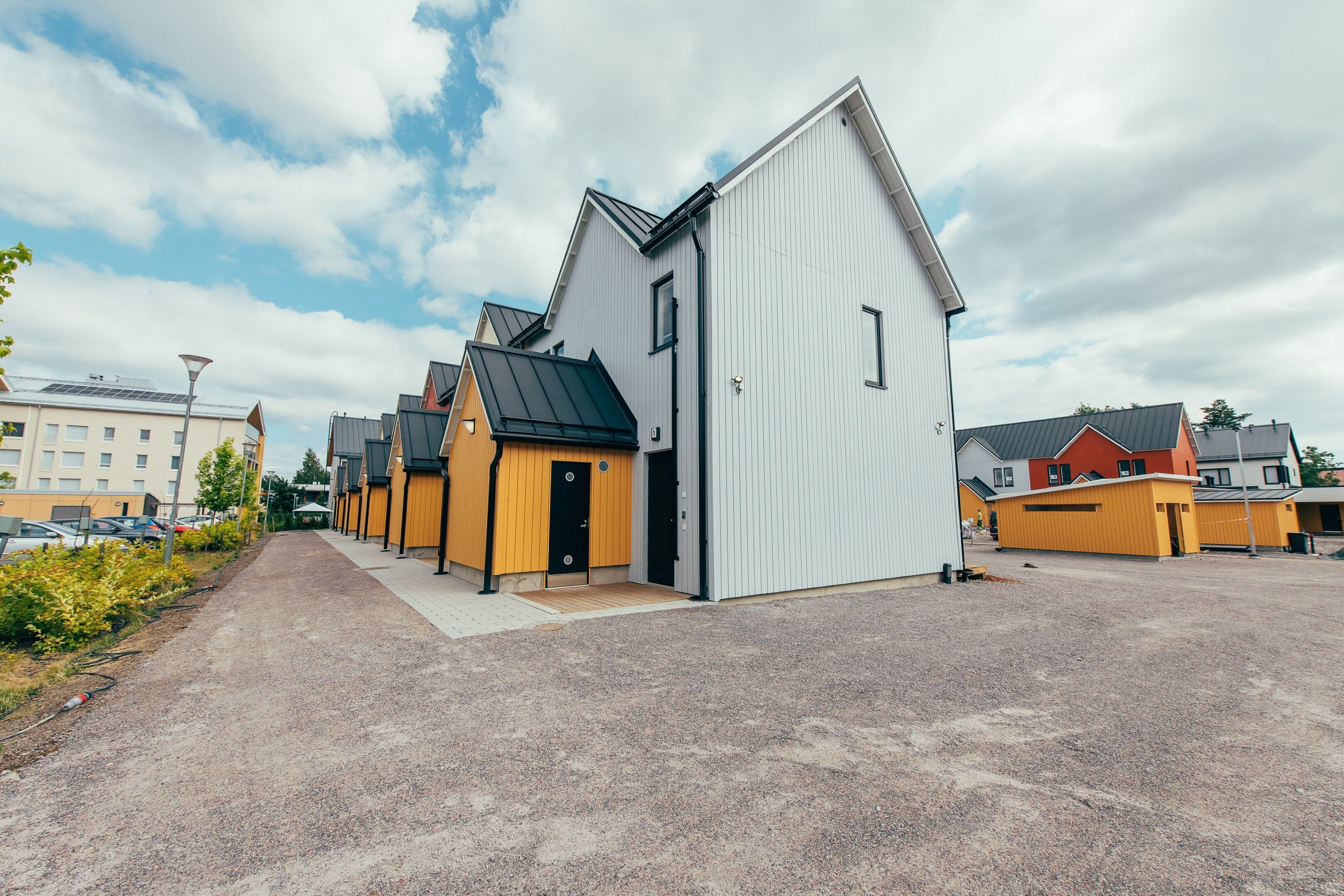 A row of modern buildings with a gravel driveway and a clear sky.