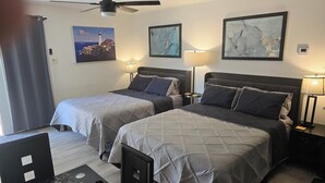 Habitación de hotel con dos camas, ventilador de techo y obras de arte en las paredes.