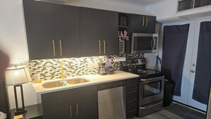 Cocina moderna con armarios oscuros, pileta de acero inoxidable, microondas y lavavajillas.