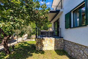 Une maison moderne dotée d’une terrasse en pierre, d’un espace salon extérieur et d’un arbre.