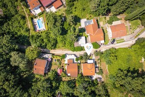 An aerial view of a residential area with multiple houses, a swimming pool, and a large water tank. - Beachside House Lara (Omisalj)